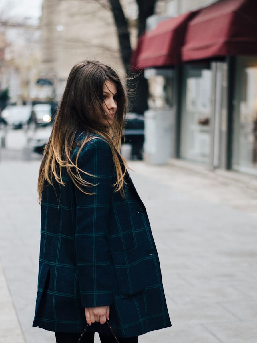 A woman in a navy checked wool blazer on a quiet street