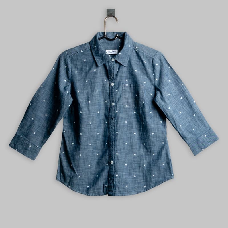A soft chambray shirt with a subtle print on a wooden hanger