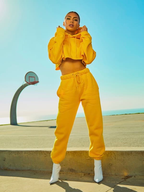 A woman in a matching yellow hooded sweatshirt and joggers