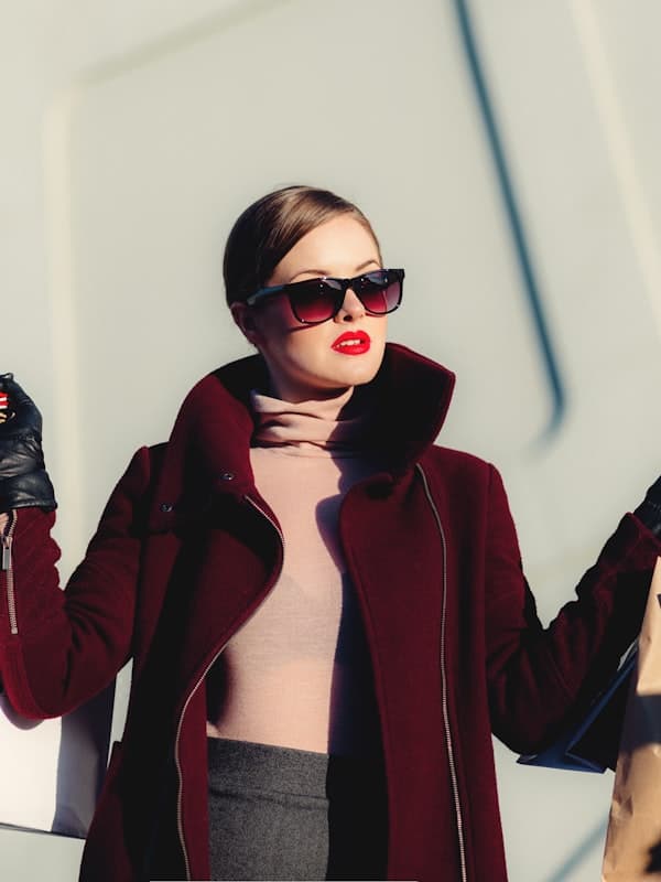 A woman in a deep burgundy wrap wool coat and leather gloves