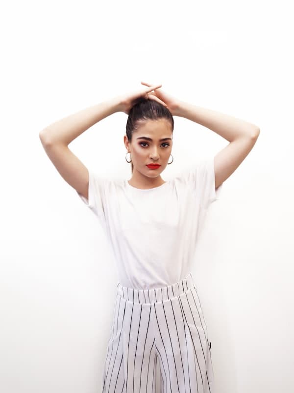 A woman in a white tee and pinstripe wide-leg trousers